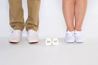 Two pairs of feet from the parents and shoes from an unborn baby, studio