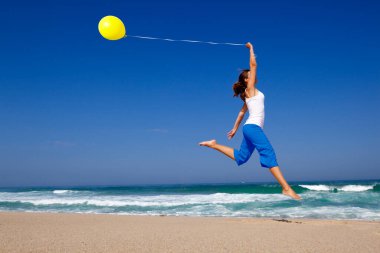 güzel ve atletik kız sahilde bir balon ile atlama