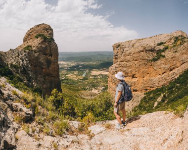 A young athletic woman stops at a viewpoint along the Mallos de Riglos circle route, The Pyrenees, Huesca, Aragon, Spain