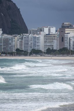 Kuma vuran dalgalara güzel bir manzara ve arkadaki binalara Copacabana Sahili, Rio de Janeiro, Brezilya