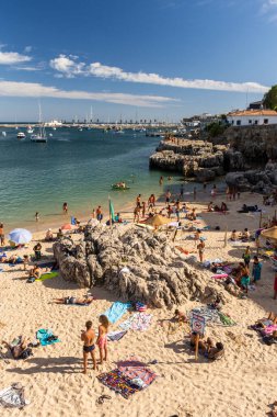 Portekiz, Lizbon yakınlarındaki Cascais 'de güneşli bir yaz haftasonu geçiren yerliler ve turistlerle dolu bir plaj.