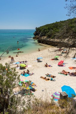 Setubal, Lizbon, Portekiz yakınlarında güneşli bir günde turist ve şemsiyelerle sahile güzel bir manzara