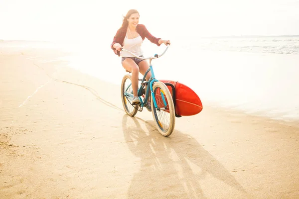 冲浪的年轻女子骑自行车在海滩上 — 图库照片
