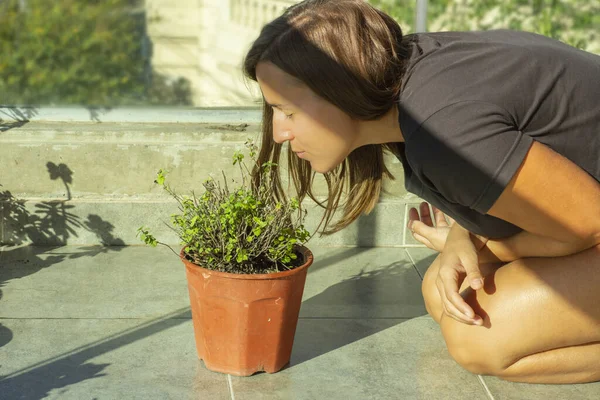 バルコニーで植物の匂いを嗅ぐ若い女性 — ストック写真