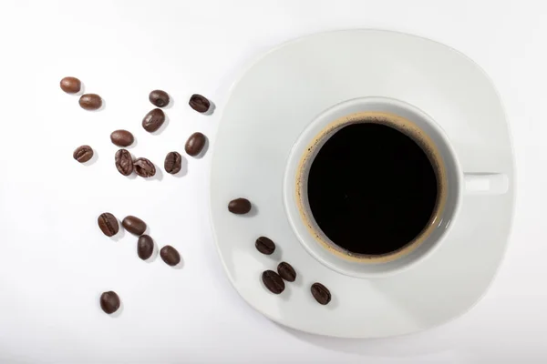 A White cup with coffee on a white background and coffee beans