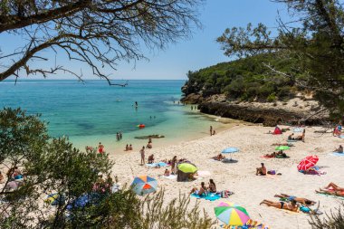 Setubal, Lizbon, Portekiz yakınlarında güneşli bir günde turist ve şemsiyelerle sahile güzel bir manzara