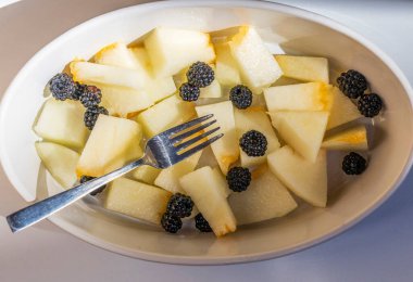 Beyaz arka planda lezzetli dilimlenmiş ananas ve peynir tabağı.