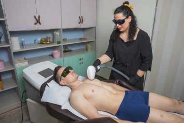 Kadın, erkek için lazer tüyü yapıyor.