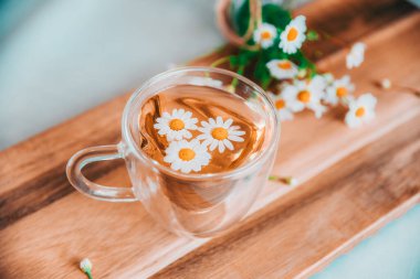 Bir fincan çiçekli bitki çayı ve ahşap arka planda fotokopi alanı olan papatya çayı..