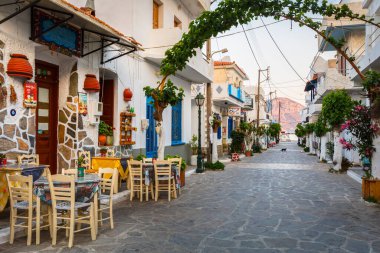 Fourni, Yunanistan - 28 Nisan 2018: Yunanistan 'ın Fourni kentinde ana cadde vith dükkanları ve bir restoranın manzarası.