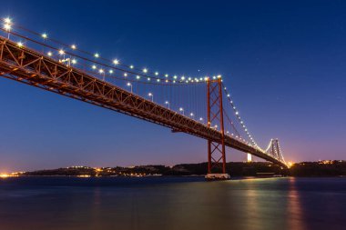 25 de Abril Köprüsü 'nün güzel manzarası Tejo Nehri üzerinde gece erken saatlerde, merkez Lizbon, Portekiz