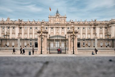 Kraliyet Sarayı 'nın muhteşem manzarası ve meydanda metal çitler boyunca yürüyen turistler.