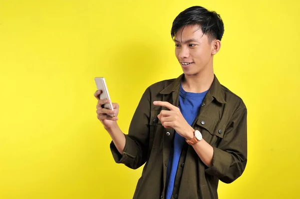 黄色の背景に隔離されたスマートフォンを使用して笑顔若い良いアジアの男の幸せ — ストック写真