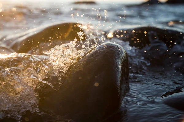 湿った海岸石の上での波のブレーキの閉鎖写真夏の日没 水の飛沫 太陽光線 水滴への反射 — ストック写真