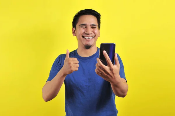 Szczęśliwy Młody Przystojny Azjata Uśmiecha Się Pomocą Smartfona Odizolowany Żółtym — Zdjęcie stockowe