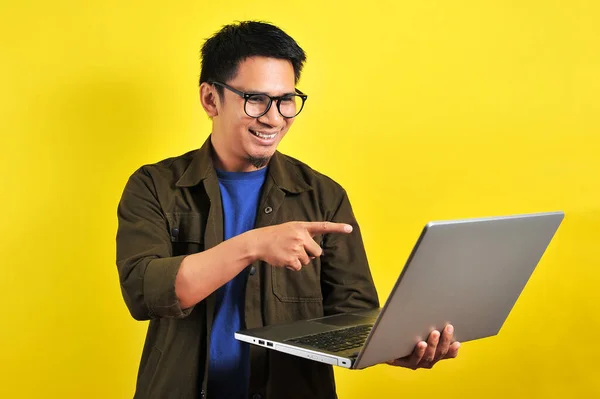Gülümseyen Yakışıklı Asyalı Genç Girişimci Dizüstü Bilgisayarını Göstererek Sarıya Izole — Stok fotoğraf