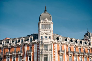 Madrid 'deki bulutsuz gökyüzünün arka planında süs duvarları ve balkonları olan tarihi binanın alçak açısı