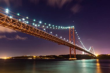 25 de Abril Köprüsü 'nün güzel manzarası Tejo Nehri üzerinde gece erken saatlerde, merkez Lizbon, Portekiz