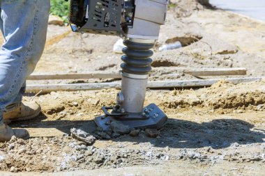 Kaldırım boyunca inşaat sürecinde kum zemininde zıplayan çekiç titreşimi