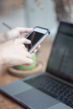 Kahve dükkanında akıllı telefon kullanan bir kadın.
