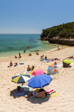 Setubal, Lizbon, Portekiz yakınlarında güneşli bir günde turist ve şemsiyelerle sahile güzel bir manzara