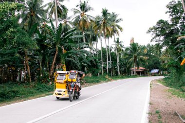 Yerel bir motosikletçi açık bir yolda geçerken el sallıyor.