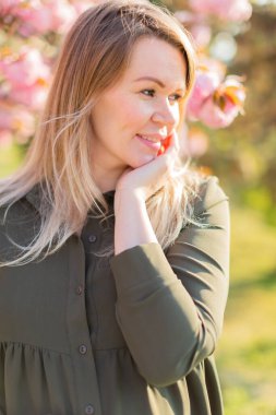Baharda parkta sakura ağaçlarıyla çilli, hamile bir kadın. Saha hamileliğinin sığ derinliği.