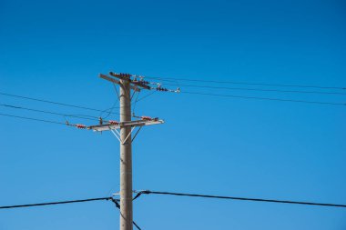 Yüksek voltaj kulesi. Elektrik teli. Açık mavi gökyüzüne karşı elektrik endüstrisi aktarım teknolojisi. Enerji dağıtım pilonu. Elektrik kablosu altyapı direği. Şehir inşaatı