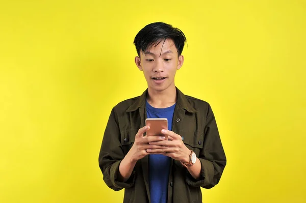 Zszokowana Twarz Azjaty Białej Koszuli Patrząc Ekran Telefonu Żółtym Tle — Zdjęcie stockowe