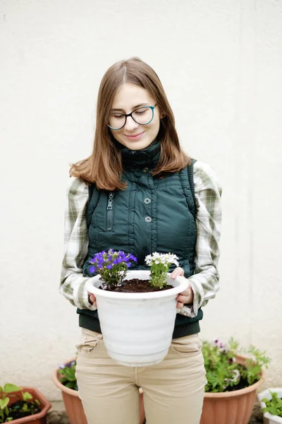 woman transplants flowers into flowerpots near her house in the garden