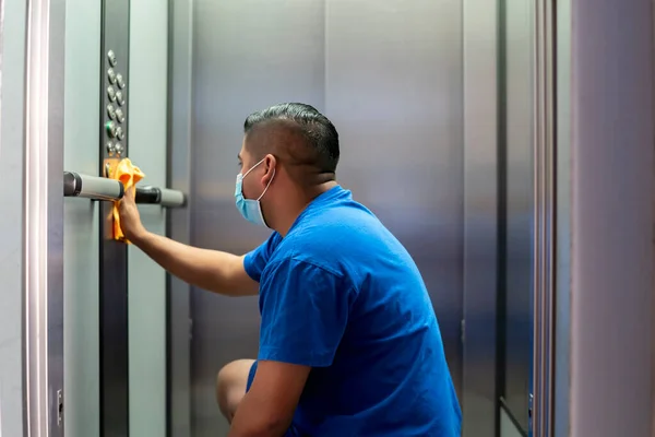 maintenance personnel disinfecting elevator buttons to avoid covid19