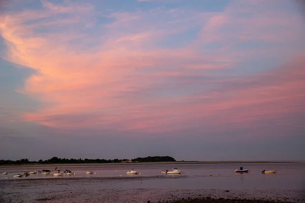 Crescent moon in the sunset sky over the ocean harbor in New England.