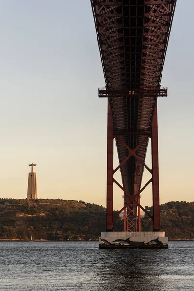 ポルトガル リスボン中心部の日没時にテジョ川とクリスト レイ像の上に25 Abril Bridgeへの美しい景色 — ストック写真