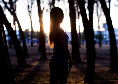 Günbatımında yalnız ormanda çekici genç bir kadın.