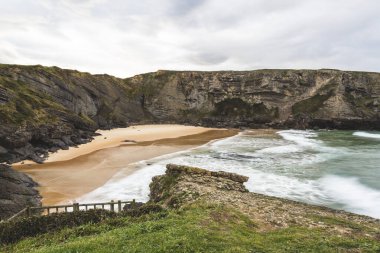 İspanya, Cantabria 'da bulutlu bir günde dalgalı Antuerta plajı