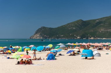 Setubal, Lizbon, Portekiz yakınlarında güneşli bir günde turist ve şemsiyelerle sahile güzel bir manzara
