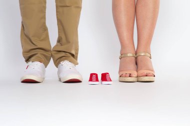 Two pairs of feet from the parents and shoes from an unborn baby, studio