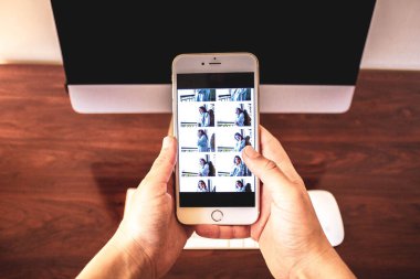 Bilgisayarın önünde cep telefonunu tutan el.