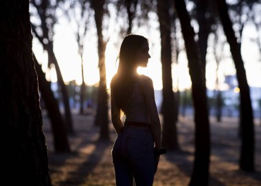 Günbatımında yalnız ormanda çekici genç bir kadın.