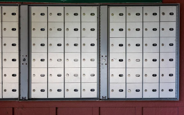 市区综合大楼棕色墙壁上挂着一排排上锁的金属信箱 — 图库照片