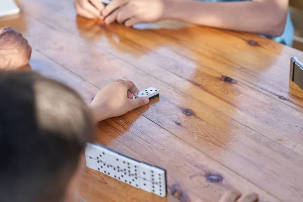 People playing dominoes on the wooden table, close-up view