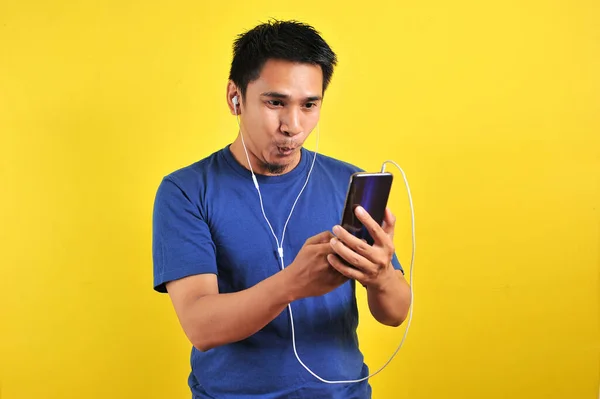 兴奋的亚洲男人的画像惊讶地发现网上有一首流行的歌曲 在黄色背景下被隔离开来 — 图库照片