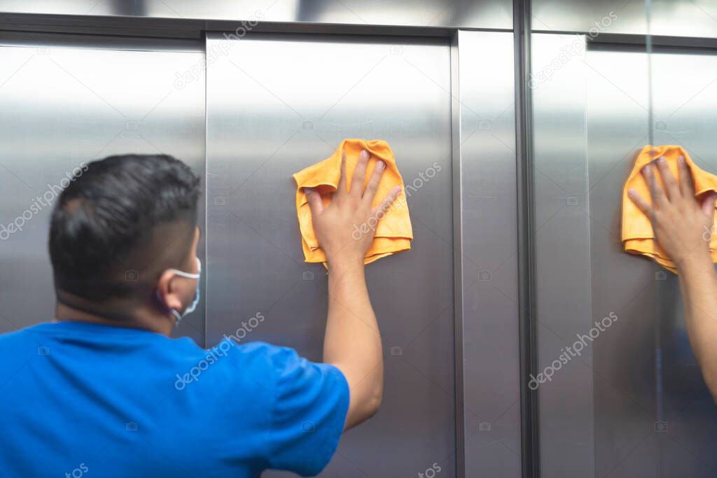 maintenance staff disinfecting the interior of the elevator to avoid covid19