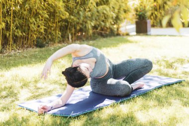 Bahçede minderle yoga yapan genç bir kız.