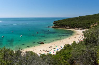 Setubal, Lizbon, Portekiz yakınlarında güneşli bir günde turist ve şemsiyelerle sahile güzel bir manzara
