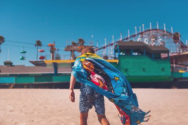 Çocuk sahilde poz veriyor ve oynuyor.