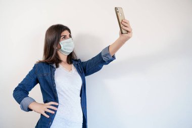 Tıbbi maske takan bir kadın selfie çekiyor..