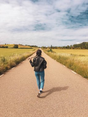 Yüzü maskeli genç bir kız tarlanın ortasında bir yolda
