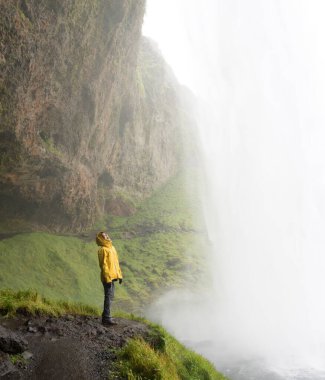 Genç bayan yürüyüşçü İzlanda 'daki şelaleden su içiyor.