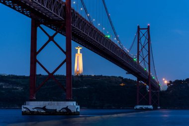 25 de Abril Köprüsü 'nün güzel manzarası Tejo Nehri ve Cristo Rei Heykeli üzerinde gecenin erken saatlerinde, merkez Lizbon, Portekiz